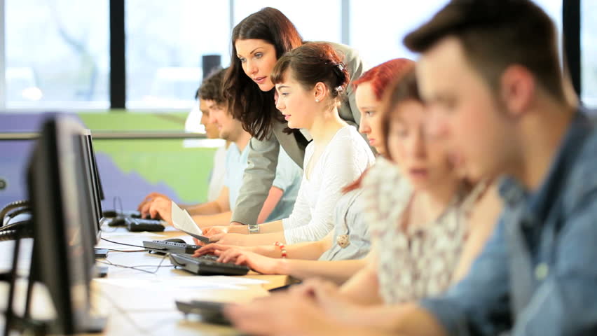 Female college lecturer teaching online young multi ethnic students in computer room
