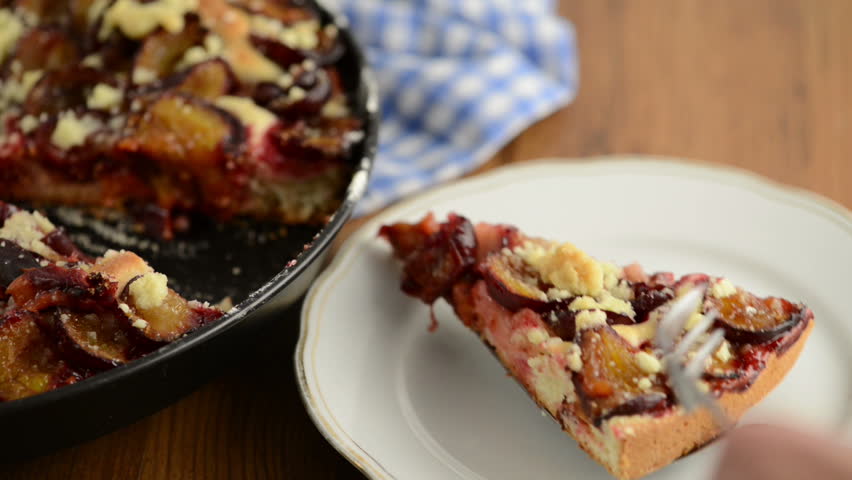 take a piece of plum cake of crumpet with a cake fork on a plate 