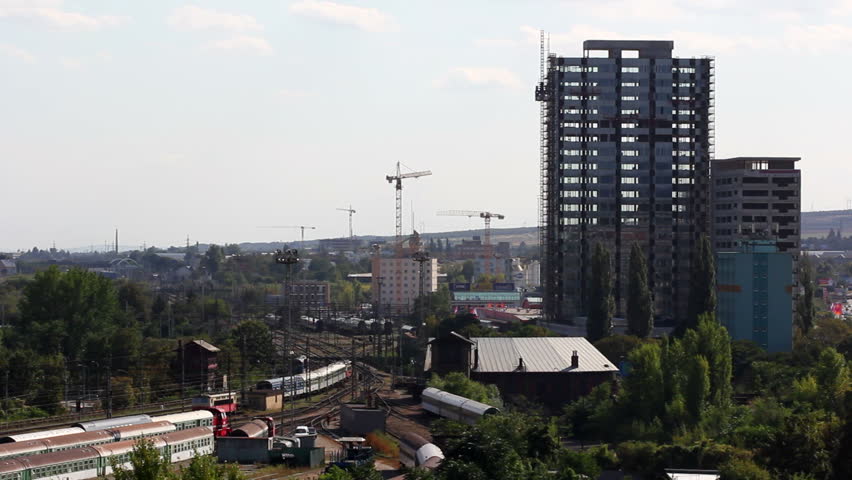 Train goes away near incomplete construction building / Construction and railway in town