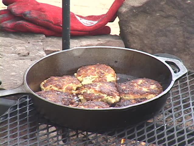 Fried tuna patties being removed from cast iron skillet