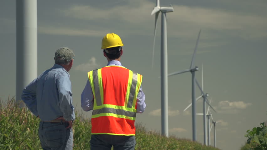 Farmer and engineer looking at windmills, cornfields