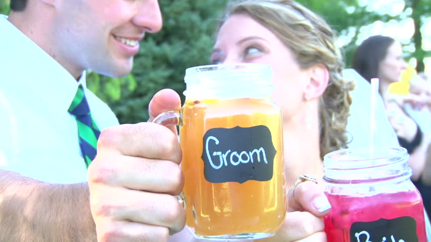 Model released bride and groom kiss and cheers their beverages on their wedding day.