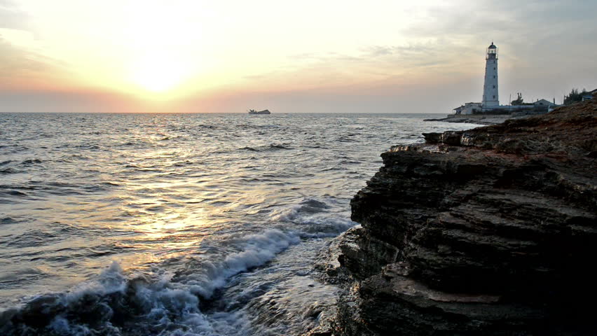 Lighthouse and wreck'd ship at sunset
