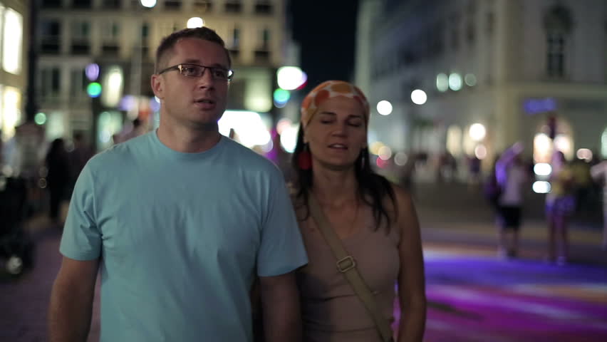 Young couple walking together in night city, steadycam shot
