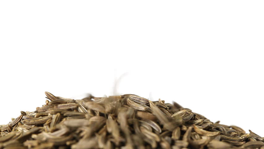 Cumin or caraway seeds falling and piling up isolated on white background