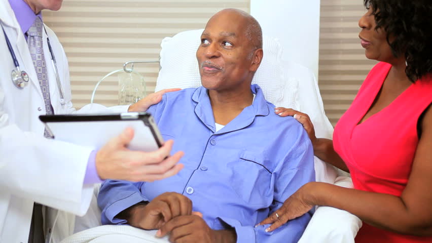 Treatment records older ethnic male patient being checked by medical staff using wireless tablet