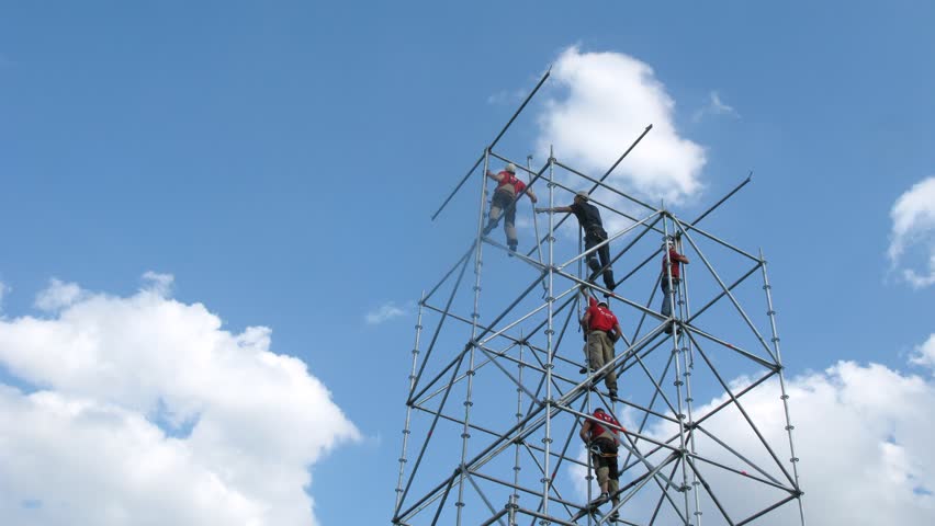 Team of climbers mounts tower against blue sky, time lapse