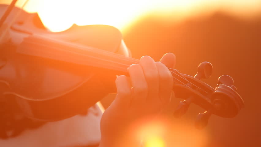 Playing fiddle outdoors at sunset 