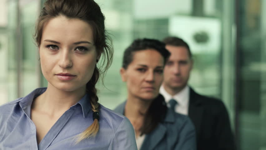 Serious looking businesspeople in front of officebuilding
