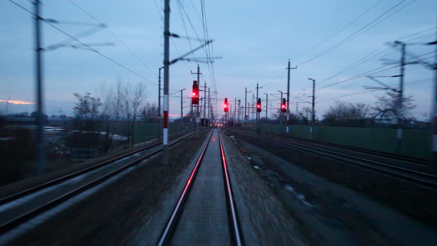 Train goes by rail near with inhabited locality and traffic light