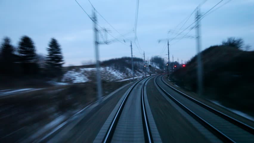 Train goes by rail near with inhabited locality in evening