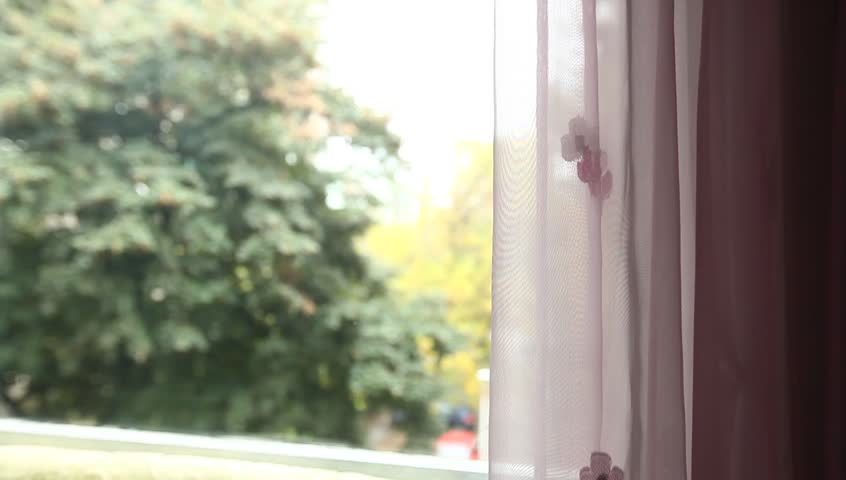 Young adult woman comes to window, finger draws and speaks.
