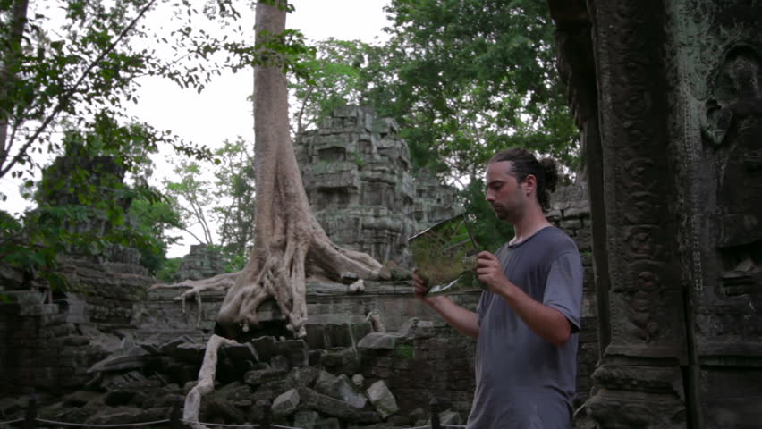 Visitor reading tourist information map in Ta Prohm temple, Angkor