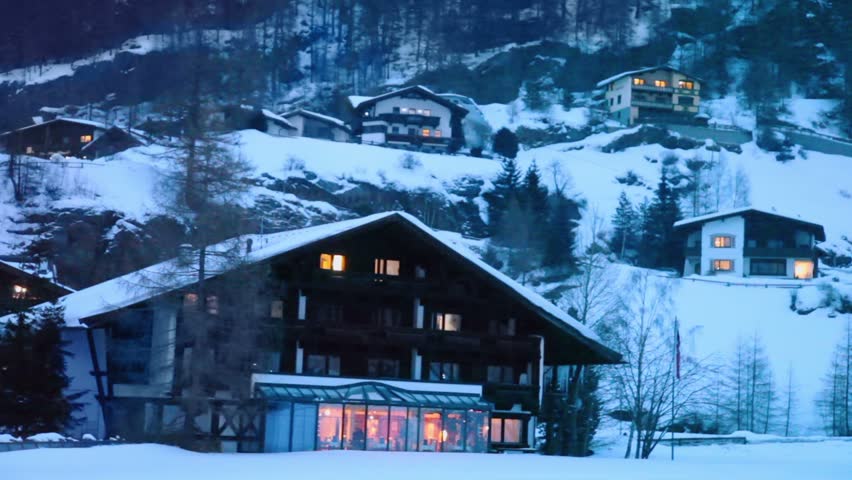 Small wooden inn at ski resort village in mountains at winter evening
