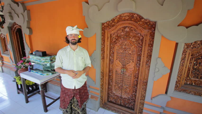 Caucasian man in Balinese clothes saluting Asian style both hands