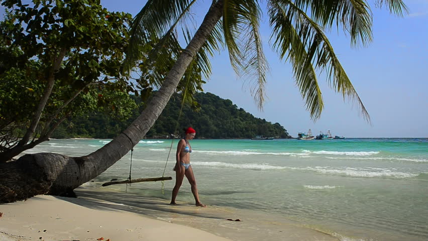 Girl in a red bandana going from swing lengthwise beach on a sunny day