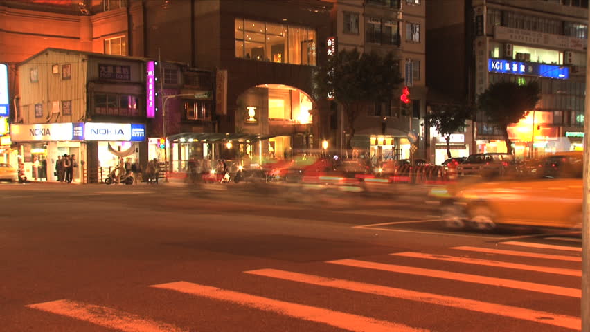 TAIPEI, TAIWAN - CIRCA 2012: Taipei downtown traffic with cars and scooters at a crossroad in the evening