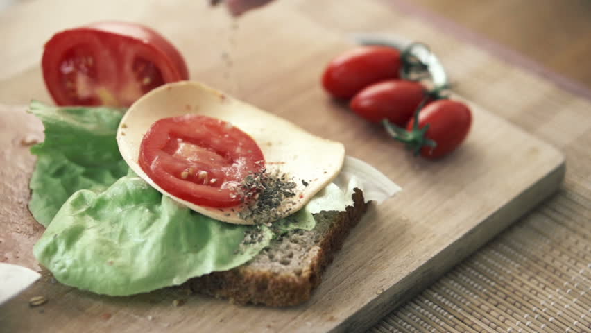 Hand sprinkle spices on tasty sandwich, slow motion shot at 240fps
