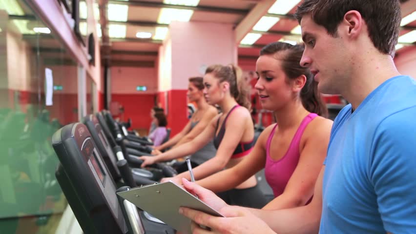 Trainer talking to woman on exercise bike in gym