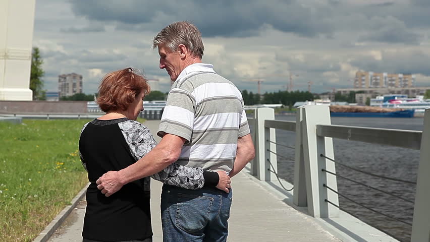 Elderly husband and wife waving hands and going forward. Neva River Embankment, St. Petersburg