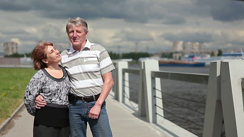 Senior husband and wife kissing each other and smiling. The Neva River Embankment, St. Petersburg