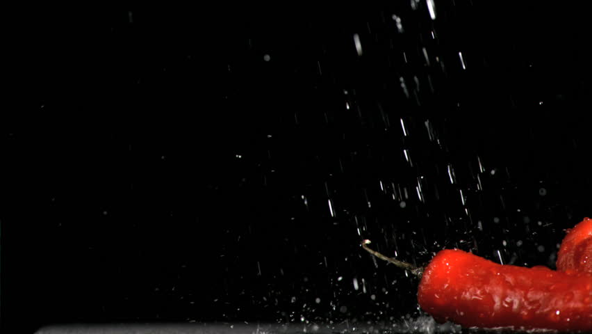 Colorful vegetables in super slow motion being soaked against a black background