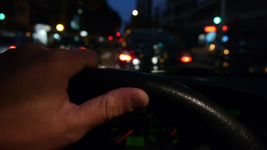 Driving at night on the city. -Hand on steering wheel close up. POV.