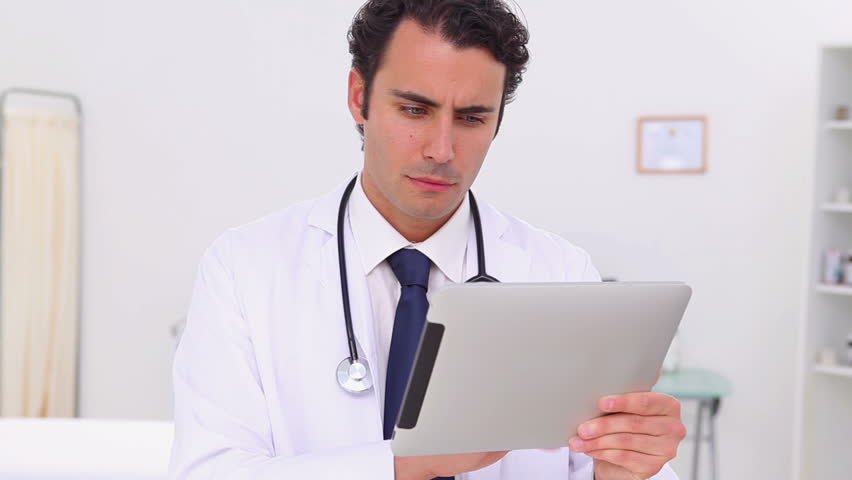 Serious doctor using a touchscreen in his office