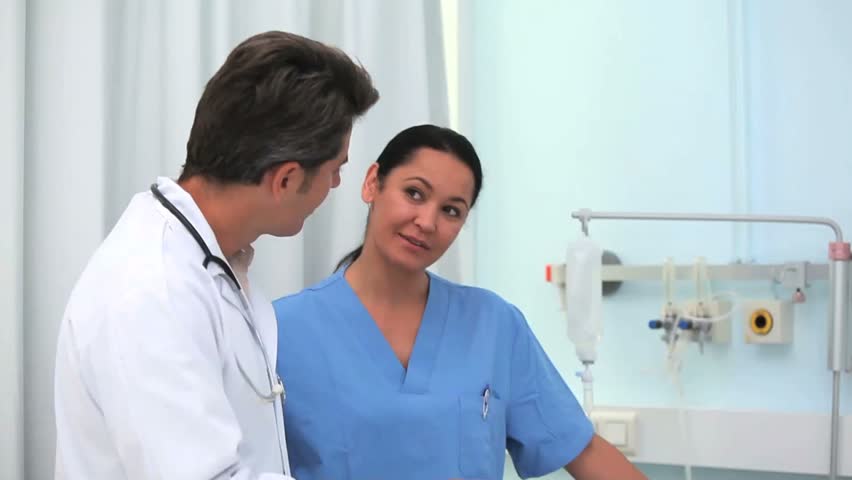 Doctor and nurse smiling to a patient in hospital ward