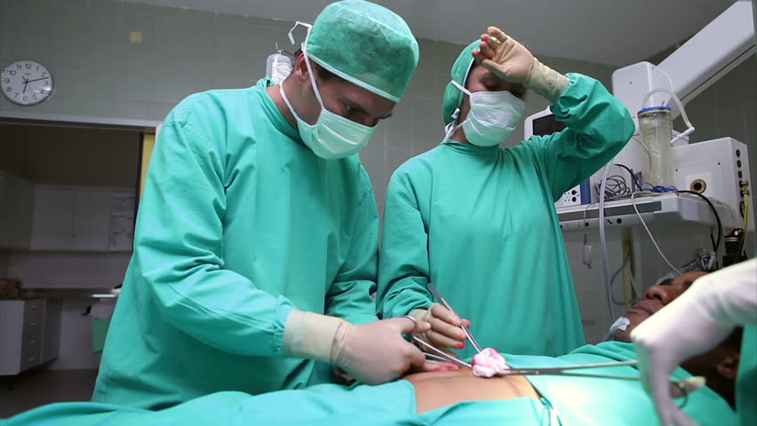 Serious doctors looking at a patient in hospital ward
