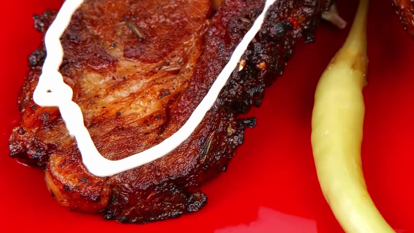 served savory plate: meat ribs on red with tomatoes and red hot peppers