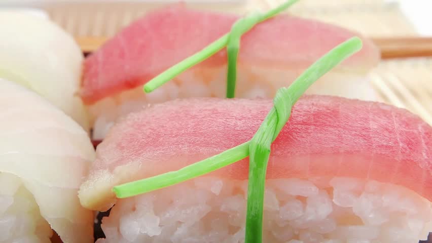 Japanese Cuisine - Different Types of Nigiri Sushi : Tuna (maguro) Salmon (sake) and Eel (unagi) with Wasabi and Ginger on bamboo mat isolated over white background