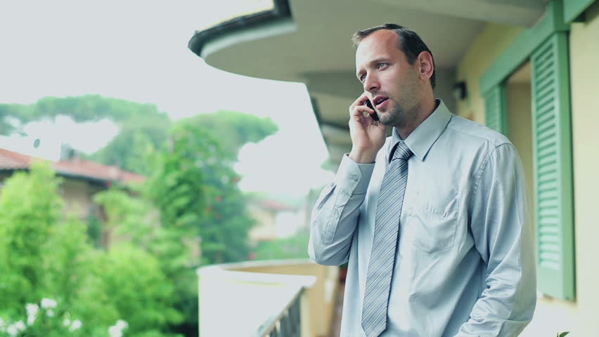Businessman talking on cellphone on his balcony
