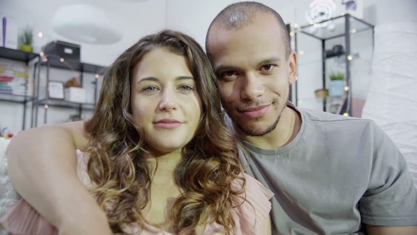 Computer screen's point of view of man and woman video chatting. Looking directly at camera and smiling and waving.