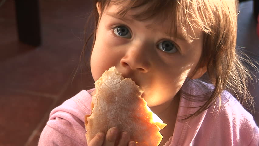 Young girl biting a piece of bread

