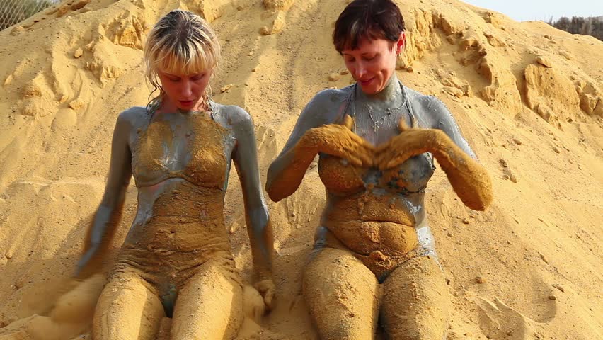Woman and girl smeared with mud and sand.
