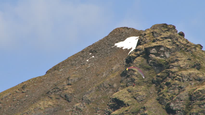 Paraglider gliding smoothly past a steep mountain slope makes smooth turns at Hatcher Pass in Alaska.