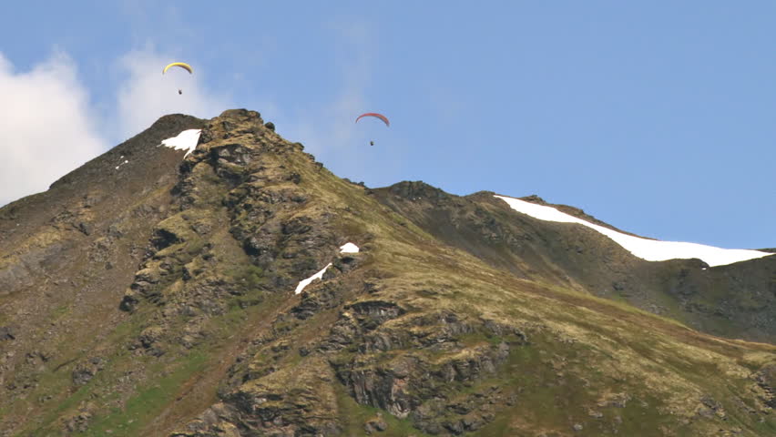 Paragliders soaring gracefully above the mountain ridges of Hathcer Pass in the Talkeetna Mountain Range in Alaska.