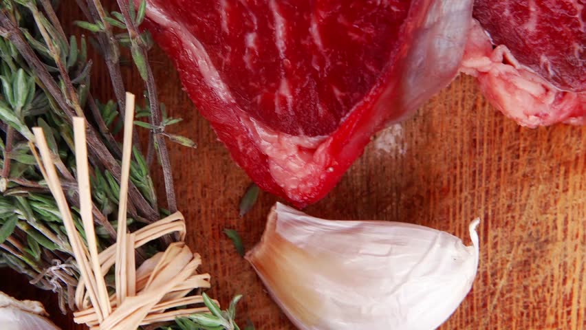 fresh raw beef meat fillet flesh with peppercorn and thyme ready to grill on wood figured old style board isolated over white background