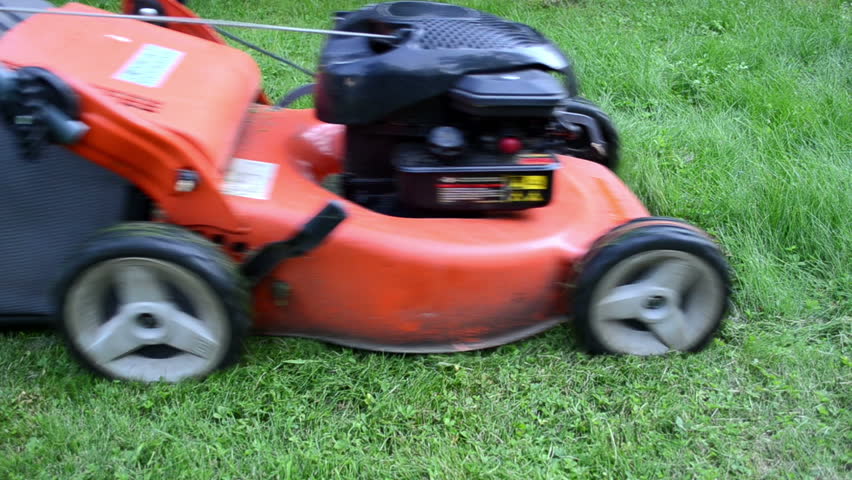 Worker in rubber boots drive meadow grass cutter mower