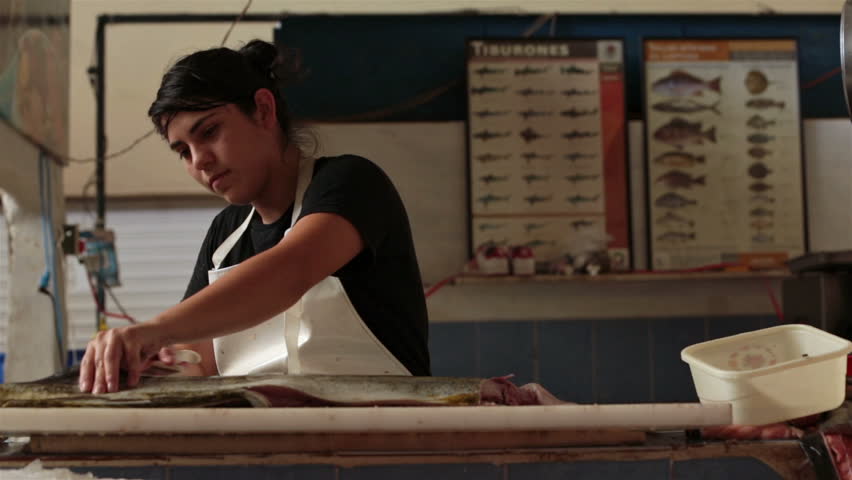 PUERTO VALLARTA, MEXICO NOV 2012: Young woman in local fish and meat market works for little pay in  the hard hit Mexican economy. Hard hit economy supports local non tourism jobs.