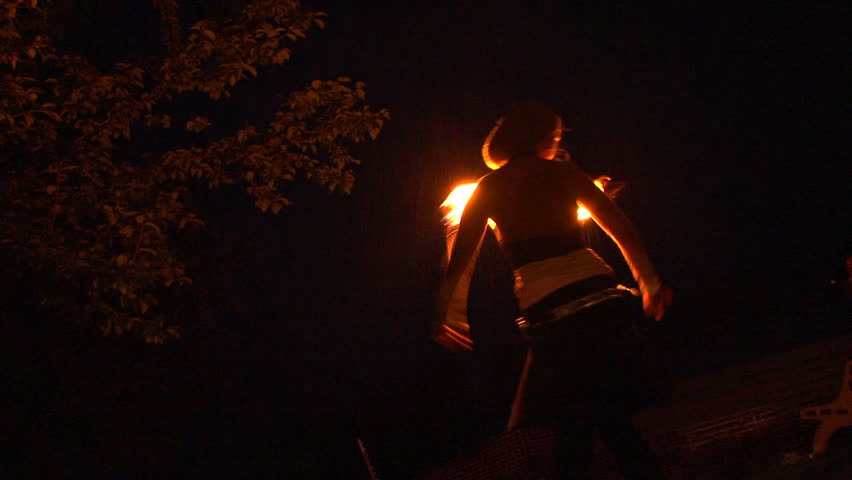 Ninilchik, AK CIRCA 2011: Rain doesn't dampen the poise and grace of this young woman dancing with fire batons (torches).