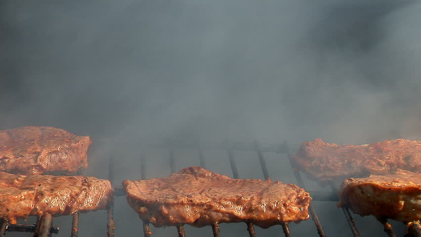 Beef stake barbecue cooked outdoors, close-up, smoke and nature
