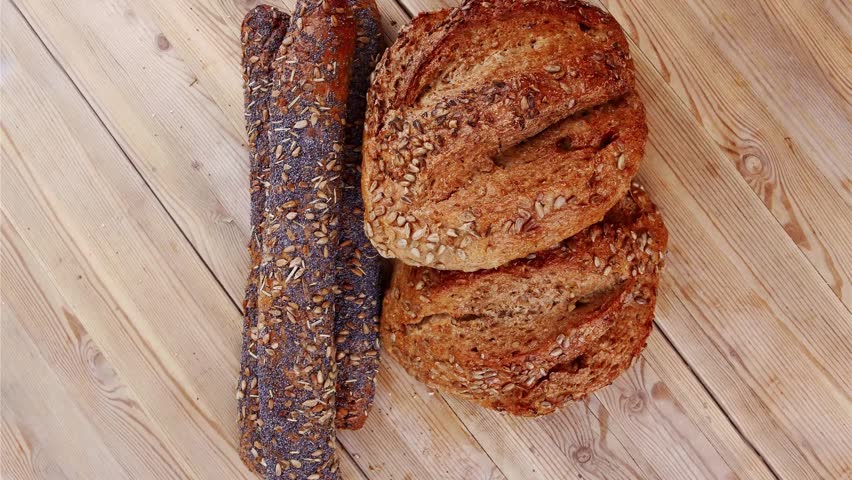 delicacy french rye breads and baguettes topped with sunflower and poppy seeds over wooden table
