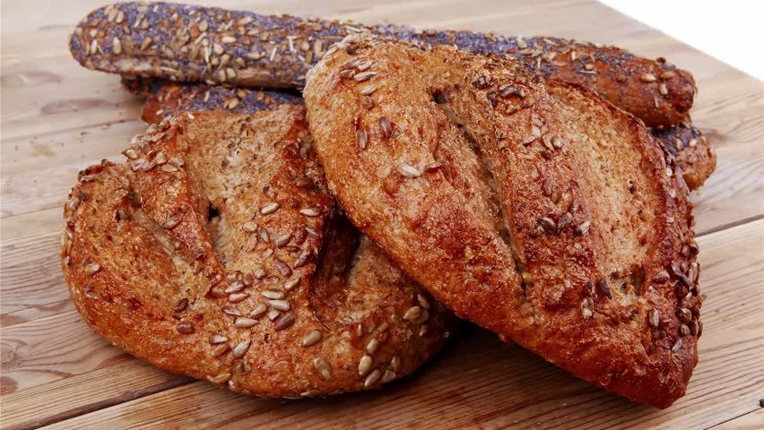 delicacy french rye breads and baguettes topped with sunflower and poppy seeds over wooden table