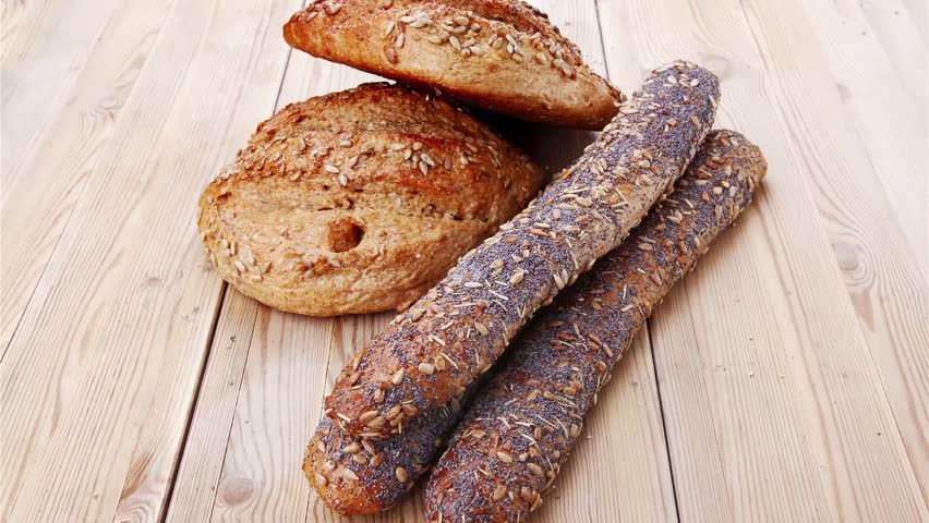 delicacy french rye breads and baguettes topped with sunflower and poppy seeds over wooden table