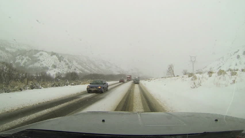 NEPHI, UTAH 26 DEC 2012: Traffic on winter snow blizzard rural mountain road. Ice and snow on road. First person point of view (POV) through drivers windshield. Rural farm community mountain roads.