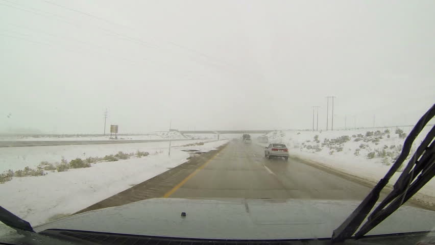 NEPHI, UTAH 26 DEC 2012: Winter highway driving snow and ice on road. Ice and snow on road. First person point of view (POV) looking through drivers windshield. Rural farm community.