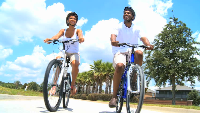 Fit & healthy young African American couple enjoy being outdoors cycling together