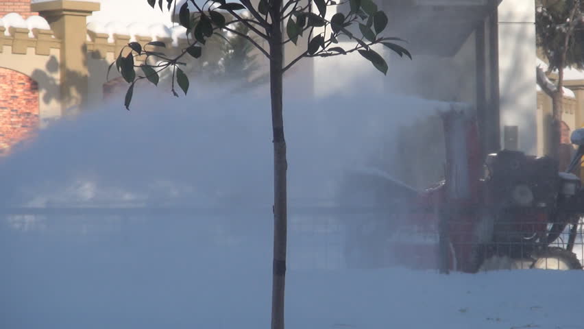 Worker Clearing the Snow Using a Snow Blower